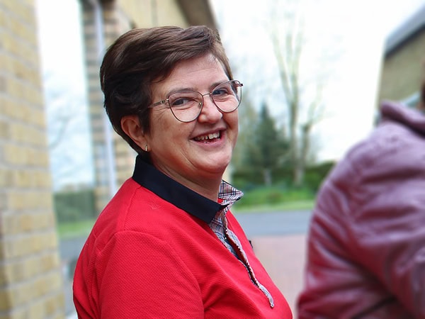 Een medewerker in rode bedrijfskleding met een hartelijke lach