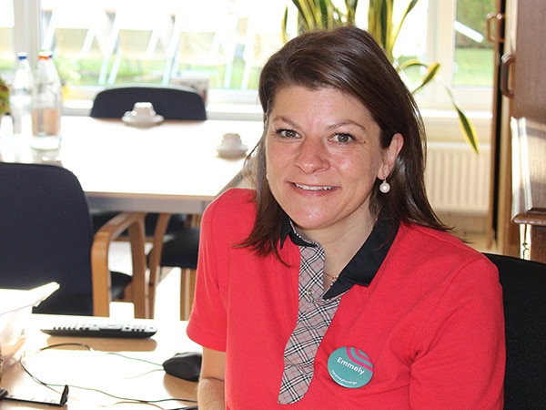 Een medewerker in rode uniform in een lichte kantooromgeving