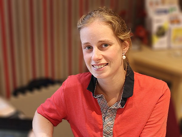 Een jonge medewerker in rode bedrijfskleding met een vriendelijke glimlach