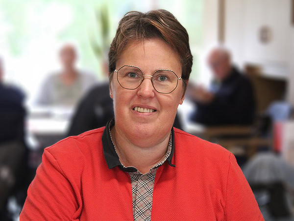 Een servicemedewerker in rode bedrijfskleding met een vriendelijke uitstraling