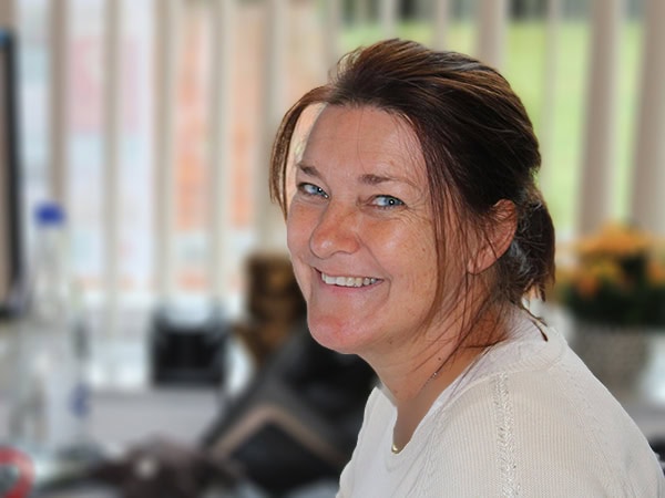 Een medewerker in een lichte trui met een warme, verwelkomende glimlach