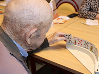 Bewoner bekijkt speelkaarten in een speciale kaarthouder tijdens een spelletje