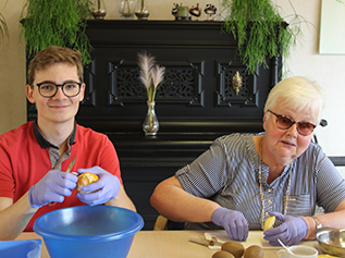 Medewerker en bewoner samen bezig met een creatieve activiteit aan tafel
