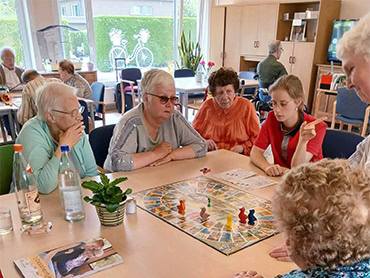 Bezoekers en begeleiders spelen samen een bordspel in het dagverzorgingscentrum
