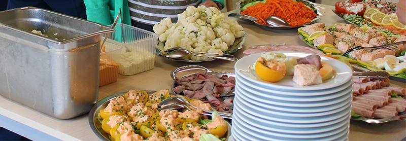Een buffet met verschillende gerechten, waaronder groenten, vlees en zalm.